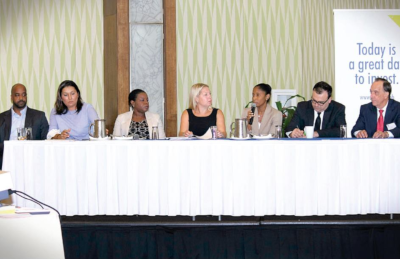 Barbados Stock Exchange. Seven men and women sitting at a table with a microphone to speak with.