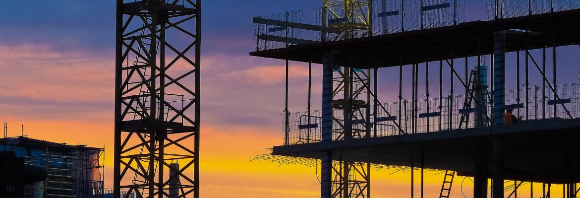 Masterbuilders Association Jamaica construction site with a beautiful orange sky background. A crane and framework of a building in the foreground.