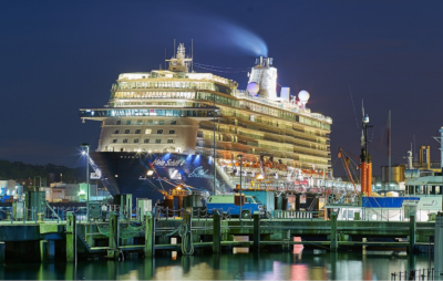A cruise ship docked at night with lights on.