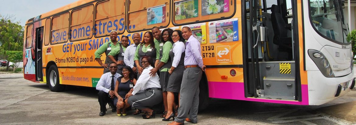 Autobusbedrijf Curaçao employees posing in front of one of their buses for a photo.