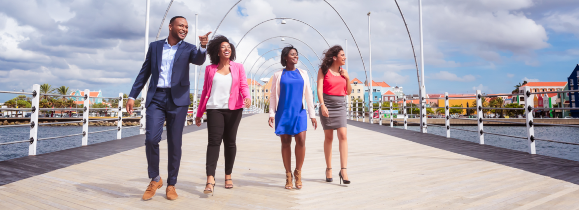 Curacao Hospitality Tourism Association. A man and three women walking on a pier with the man smiling and pointing something out.