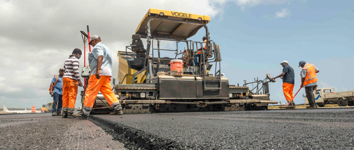 CWM Infrastructure, workers around an asphault machine work on paving a road.