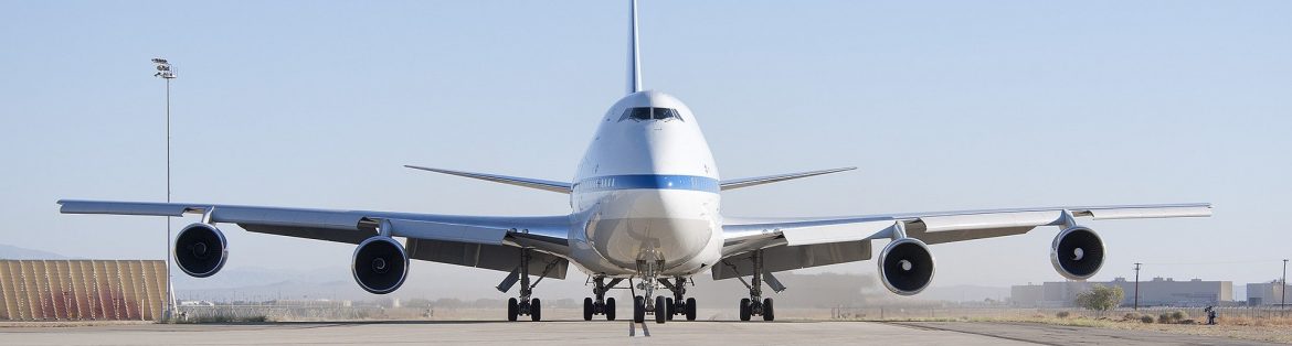A jumbo jet on the runway in motion.