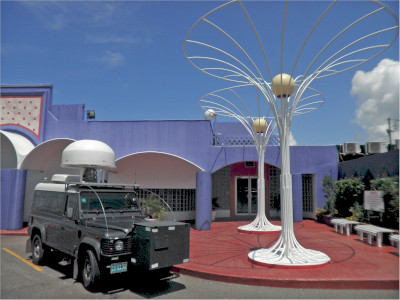 The Spectrum Management Authority of Jamaica, front of their building with a vehicle parked out front that has a communications device on top.