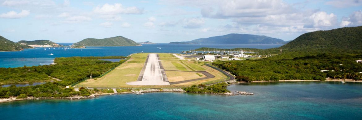 The British Virgin Islands Airports Authority. An airport runway on an island in the Caribbean with other islands in the distance and water around.