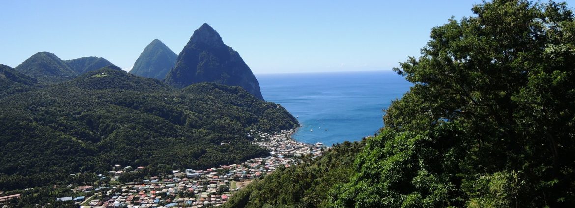 A photo of St. Lucia with the town nested between green hills/mountains in the distance.