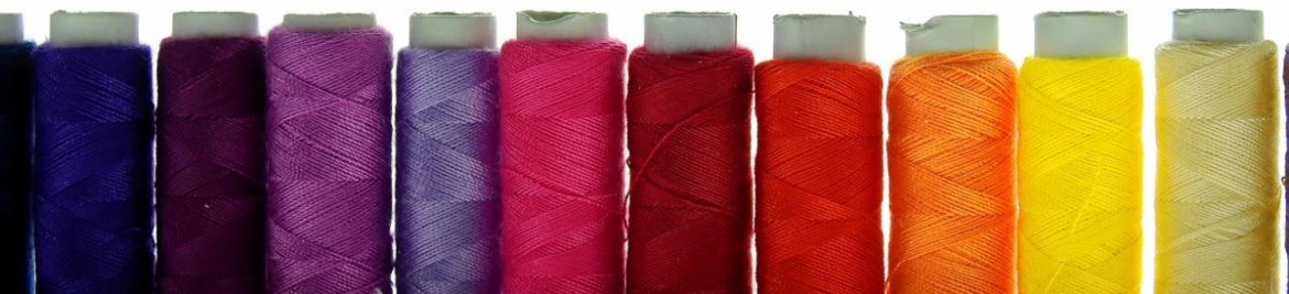 IFFBB Caribbean Fashion. A row of different colored spools of thread.