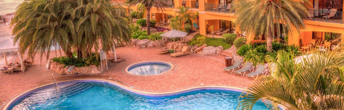 Demand for Luxury and Upscale Caribbean Accommodations on the Rise, says Expedia. A view of a Caribbean resort with palms trees and a blue pool.