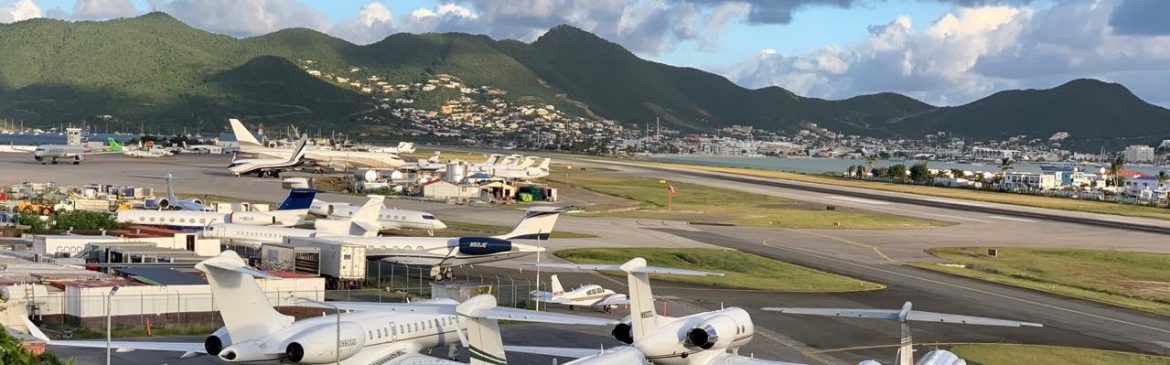 SXM Airport / Princess Juliana International Airport view of the runway with mountains behind and blue skies.