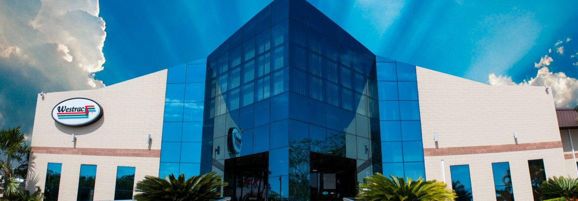 Westrac Limited Belize, front of building with blue sky and sun rays behind.