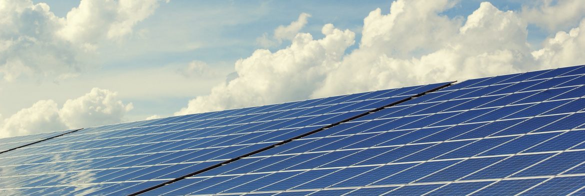 A solar panel with blue sky and clouds behind.
