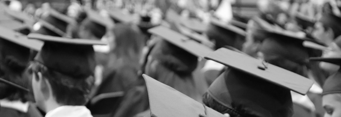 A room full of people with graduation hats on, viewing them from behind.