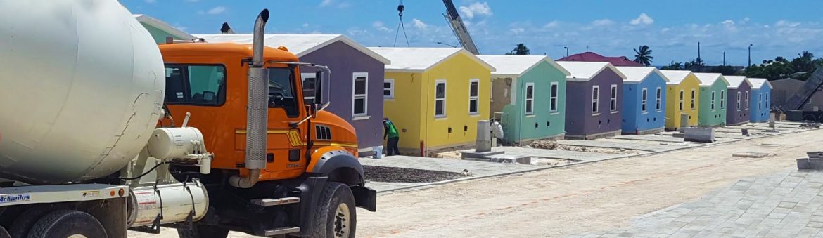 Ready-Mix Limited Barbados cement truck at a new home construction site with a row of colorful houses.