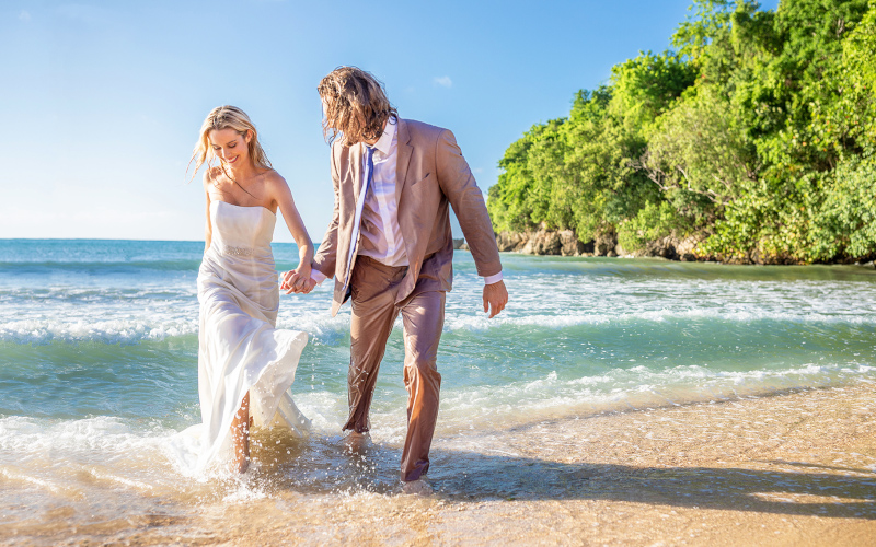Couples San Souci Jamaica, a woman and man in wedding attire playing in the beach surf.
