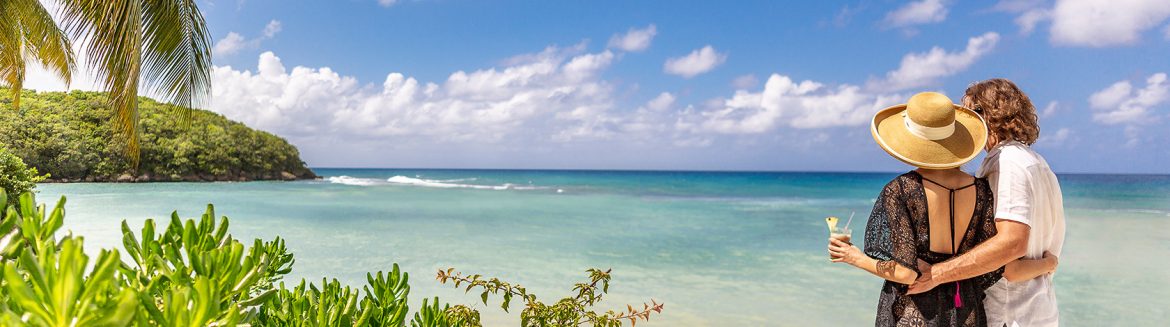 Couples San Souci Jamaica, a woman and man embracing each other looking out over the beach view in the background.